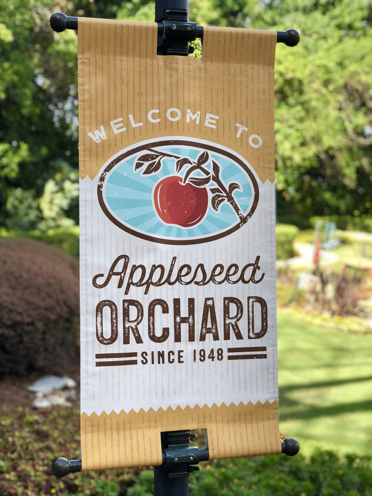 Brown, Red and White sign with an apple on it that says Appleseed Orchard