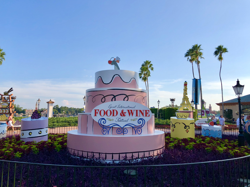 Pink cake with a little gray mouse on the top with food and wine sign