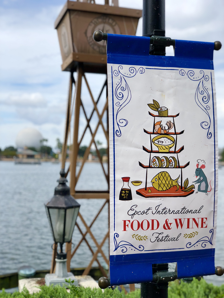 Blue and white festival flag on a post in front of water.