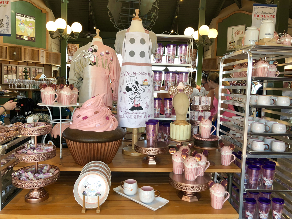 Pink and white shirts, cups and aprons on a wood table.