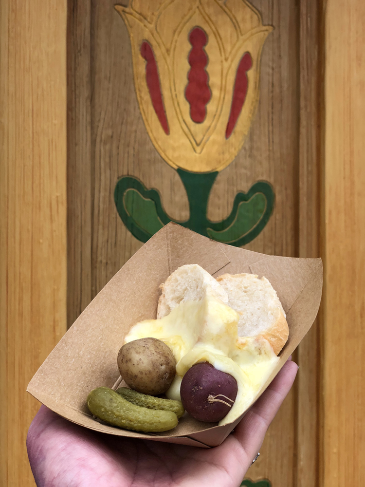 Melted cheese with pickles, potatoes and bread in a brown dish