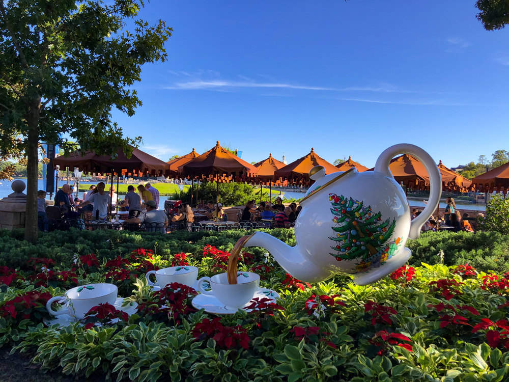 White large teapot pouring into little white teacups in a garden